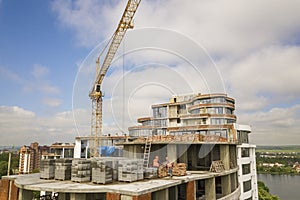 Apartment or office tall building under construction. Brick walls, glass windows, scaffolding and concrete support pillars. Tower