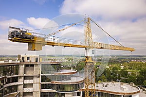 Apartment or office tall building under construction. Brick walls, glass windows, scaffolding and concrete support pillars. Tower