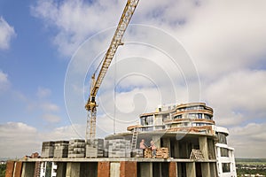 Apartment or office tall building under construction. Brick walls, glass windows, scaffolding and concrete support pillars. Tower