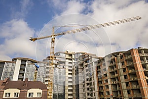 Apartment or office tall building under construction. Brick walls, glass windows, scaffolding and concrete support pillars. Tower