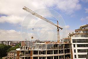 Apartment or office tall building under construction. Brick walls, glass windows, scaffolding and concrete support pillars. Tower