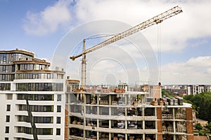Apartment or office tall building under construction. Brick walls, glass windows, scaffolding and concrete support pillars. Tower