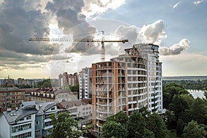 Apartment or office tall building under construction. Brick walls, glass windows, scaffolding and concrete support pillars. Tower