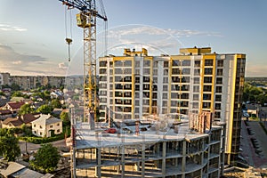 Apartment or office tall building under construction. Brick walls, glass windows, scaffolding and concrete support pillars. Tower