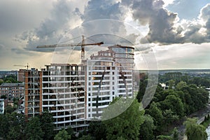 Apartment or office tall building under construction. Brick walls, glass windows, scaffolding and concrete support pillars. Tower