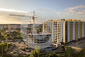 Apartment or office tall building under construction. Brick walls, glass windows, scaffolding and concrete support pillars. Tower