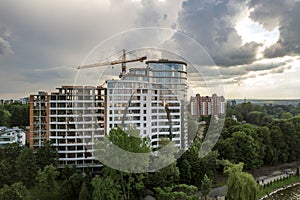 Apartment or office tall building under construction. Brick walls, glass windows, scaffolding and concrete support pillars. Tower