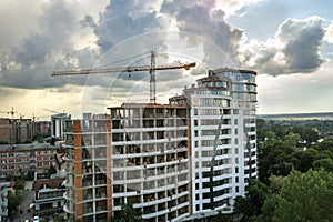 Apartment or office tall building under construction. Brick walls, glass windows, scaffolding and concrete support pillars. Tower