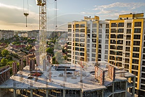 Apartment or office tall building under construction. Brick walls, glass windows, scaffolding and concrete support pillars. Tower