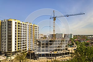 Apartment or office tall building under construction. Working builders and tower cranes on bright blue sky copy space background