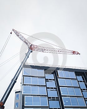 Apartment under construction. Construction crane above the building against a cloudy sky. Auckland. Vertical format