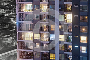 Apartment windows at night each with privacy in thier own home.