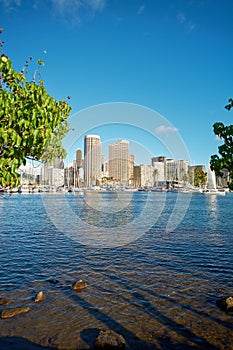 Apartments or business district beside a lagoon beach on a sunny day with a cloudy blue sky in Waikiki. A popular summer