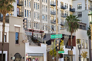 Apartments and shops along Colorado Blvd at Garfield Ave at the The Paseo surrounded by tall lush green palm trees