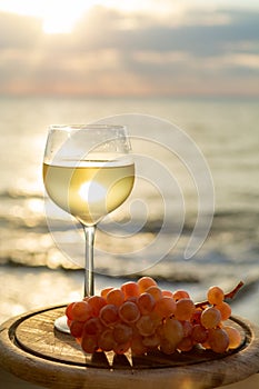 Aperitif cold white wine served in glasses with pink grapes on outdoor tessace witn sea view