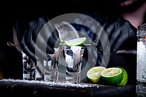 Aperitif with friends in the bar, three glasses of alcohol with lime and salt for decoration. Tequila shots, selective