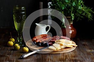 Aperitif table Meat snack, fried sausages, cheese, salami, olives and a glass of wine on a dark table Menu and restaurant concept