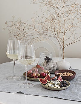 Aperitif table - two glasses of white wine, fruit, cheese, nuts on the table