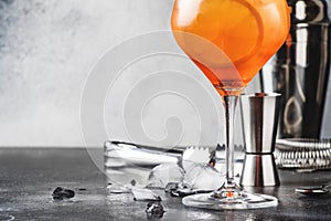 Aperol spritz cocktail in big wine glass, summer Italian low alcohol cold drink, dark bar counter background with tools, copy