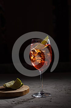 Aperol Spritz cocktail with prosecco, aperitif and soda water and slice of lemon on black background