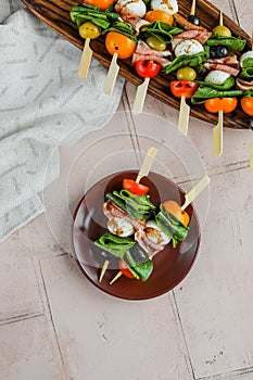 Apetizers on wooden skewers. Snacks from mozzarella, cherry tomatoes, salmon, spinach and olives.