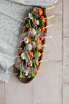 Apetizers on wooden skewers. Snacks from mozzarella, cherry tomatoes, salmon, spinach and olives.