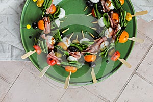 Apetizers on wooden skewers. Snacks from mozzarella, cherry tomatoes, salmon, spinach and olives.