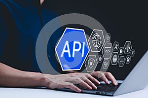 API - Application Programming Interface Concept. A programmer types on a laptop, with digital icons representing technology and