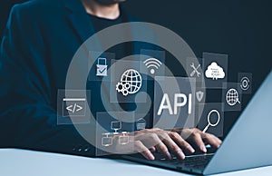 API Application Programming Interface Concept. A programmer types on a laptop, interacting with digital icons representing API