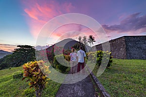 Api volcano at sunset, couple looking at view from Banda Naira fort, Maluku Moluccas Indonesia, Top travel tourist destination, photo