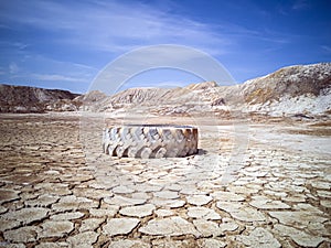 Apocalyptic landscape. The tire from the truck lies on cracked and scorched land. Solidified white Earth surface. A planet without