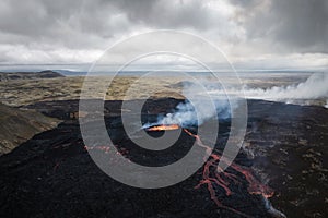 Apocalyptic surroundings of an erupted volcano, lava and smoke spreading, aerial
