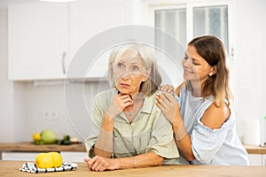 Apologetic adult daughter asking for forgiveness from her upset elderly mother after home disagreements