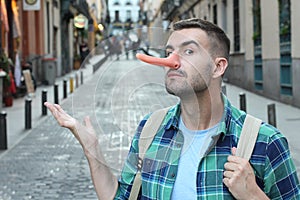 Apologetic man with a very long nose outdoors photo