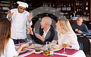 Apologetic pizzeria chef talking to dissatisfied guests