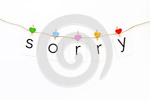 Apologise concept. Cute heart icons garland with text sorry on white background top view copy space