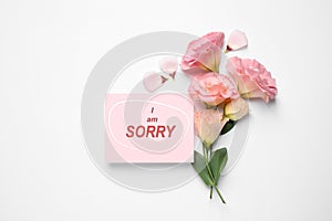 Apology. Pink card with circled phrase I Am Sorry and beautiful Eustoma flowers on white background, flat lay. Space for text