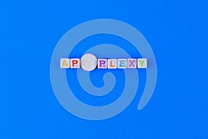 APOPLEXY text made in cubes, a white medical pill with a score instead of the letter O. Classic blue background photo