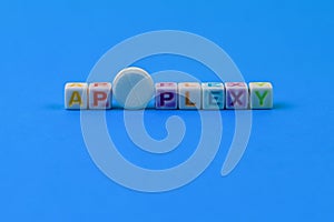 APOPLEXY text made in cubes, a white medical pill with a score instead of the letter O. Classic blue background photo