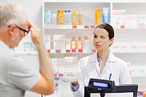 Apothecary giving drug to senior man at pharmacy photo