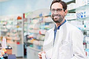 Apothecary in pharmacy standing at shelf with drugs