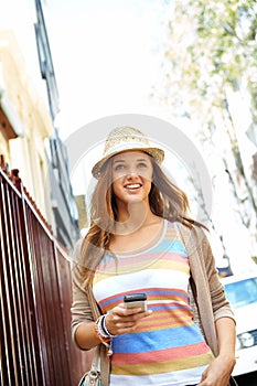 With this app Ill never get lost. A gorgeous young woman wearing casual summer clothes walking down a city street while