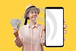 App of investment. Young smiling woman wearing a straw hat and shows a large smartphone with a white screen and holds a