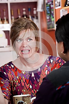 Appalled woman in coffee house with male friend