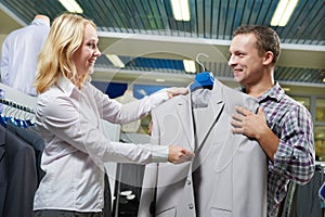 Apparel shopping. seller demonstrates formal suit to man in store photo