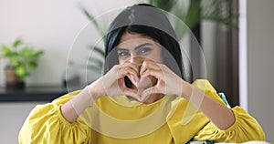 Appealing Indian woman showing heart beats sign with hands