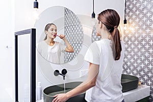 Appealing woman brushing teeth standing in the bathroom