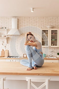 Appealing young lady in light blue outfit sitting in tragic posture