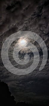 The appearance of a bright moon surrounded by clouds in the sky.