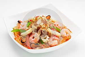 Appetising cellophane noodles with seafood in a white plate, close up on a white background
